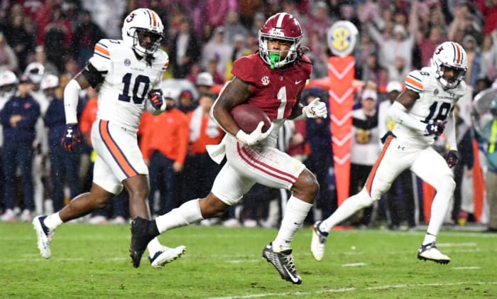 running back Jahmyr Gibbs runs holding the ball as two Auburn defenders try to catch him